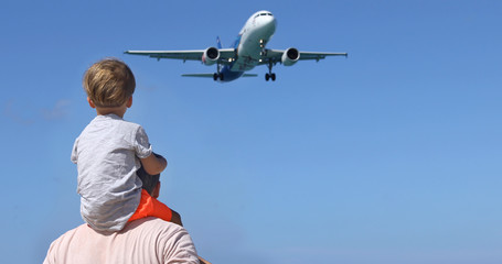 Father and son watching the landing planes. Traveling on an airplane with children