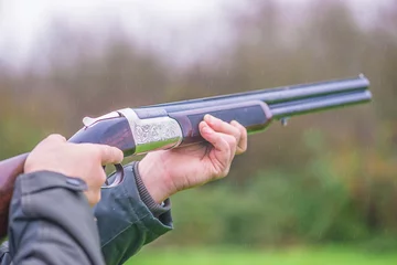 Gordijnen Hunter shooting with rifle. Close up, selective focus © stsvirkun