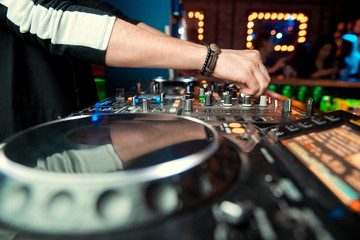 control DJ for mixing music with blurred people dancing at party in nightclub