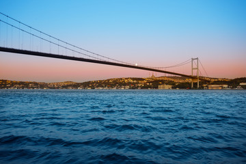 Bridge over Bosphorus in twilight dawn under bright moon