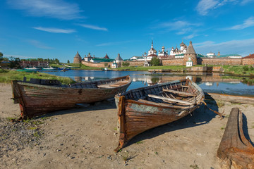 Fototapety  Old fishing boats on the shore against the background of the Transfiguration of the Solovetsky Monastery. Solovki, Russia