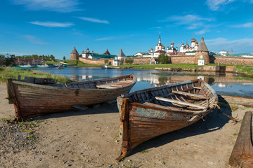Fototapeta na wymiar Old fishing boats on the shore against the background of the Transfiguration of the Solovetsky Monastery. Solovki, Russia