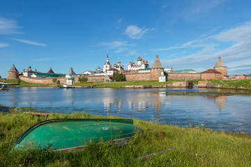 Old fishing boats on the shore against the background of the Transfiguration of the Solovetsky Monastery. Solovki, Russia - obrazy, fototapety, plakaty