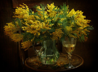 Bouquet of mimosa and a glass of white wine