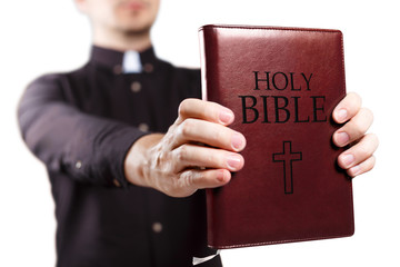 Young priest holding the Holy Bible, isolated on white background