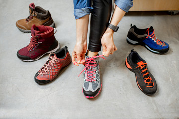 Woman trying different trail shoes for mountain hiking in the sports shop, close-up view with no...