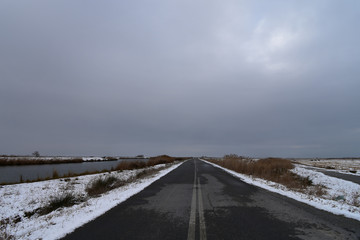 Empty asphalt country road leading to Loudias River delta in a winter day.  Axios-Loudias-Aliakmonas National Park, Greece
