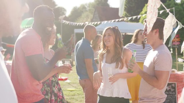 Slow Motion Shot Of Friends Enjoying Drinks At Summer Garden Fete 
