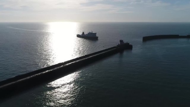 Aerial bird view footage of ferry silhouette arriving at harbor these are merchant vessels used to carry passengers vehicles and cargo across in this case the English Channel 4k high resolution