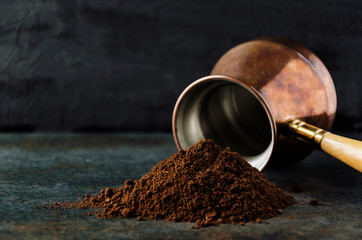 Pile of ground coffee against special pot fot it.Dark mood