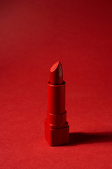 Creative concept photo of red painted lipstick on red background.