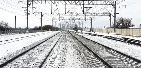  Railway in winter. Railway rails and high-voltage lines.