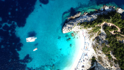 Aerial drone bird's eye view photo of sail boats docked in tropical caribbean paradise bay with white rock caves and turquoise clear sea