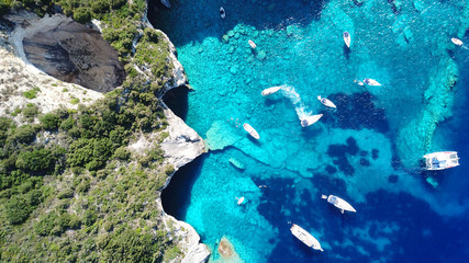 Aerial drone bird's eye view photo of sail boats docked in tropical caribbean paradise bay with white rock caves and turquoise clear sea