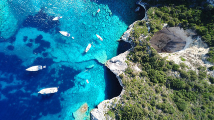 Aerial drone bird's eye view photo of sail boats docked in tropical caribbean paradise bay with white rock caves and turquoise clear sea © aerial-drone