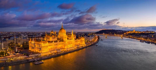 Fototapete Budapest Budapest, Hungary - Aerial panoramic view of the beautiful illuminated Parliament of Hungary with Szechenyi Chain Bridge, Buda Castle Royal Palace and colurful clouds at background at sunset