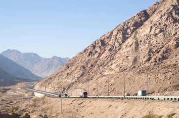 Highway in a stone desert and trucks on the road , Jordan