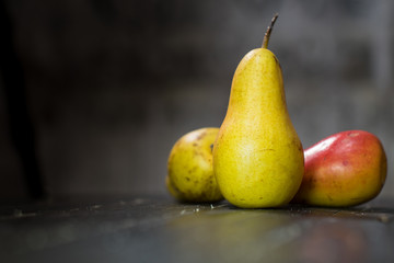 Group of ripe pears on dark rustic wooden table. Side view horizontal shot. Empty copyspace for your design.