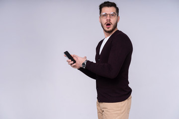 You will have problems man! Portrait of angry confused aggressive in bad mood guy shouting threatening in the loud-speaker of his smartphone, isolated on gray background.