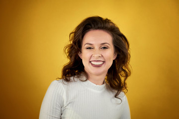 portrait of middle-aged woman smiling happily on yellow background