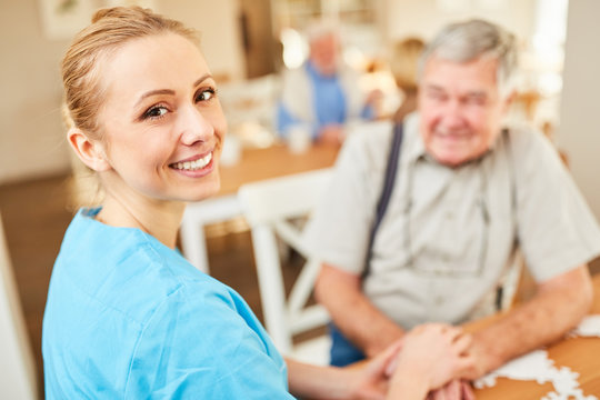 Lächelnde Pflegehilfe tröstet einen Senior