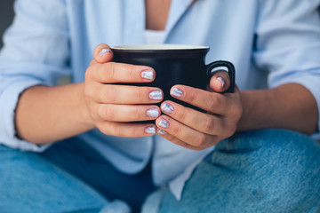 Cute girl with a beautiful manicure drinking coffee