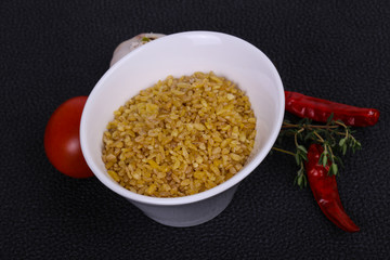 Raw bulgur in the bowl with tomatoes and garlic