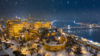 Zelfklevend Fotobehang Budapest, Hungary - Aerial view of illuminated Buda Castle Royal Palace on a winter night with heavy snowing, Szechenyi Chain Bridge and Matthias Church © zgphotography