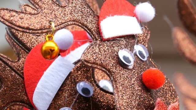 New Year and Christmas hoops on the head in the form of deer in Santa claus hats and bell in the ear close up view. The spirit of Christmas and New Year