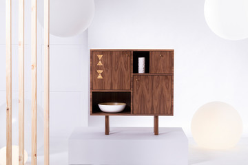 Fashionable dark wooden commode in bright interior
