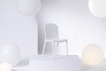 White chair on platform in bright showroom interior with big balloons