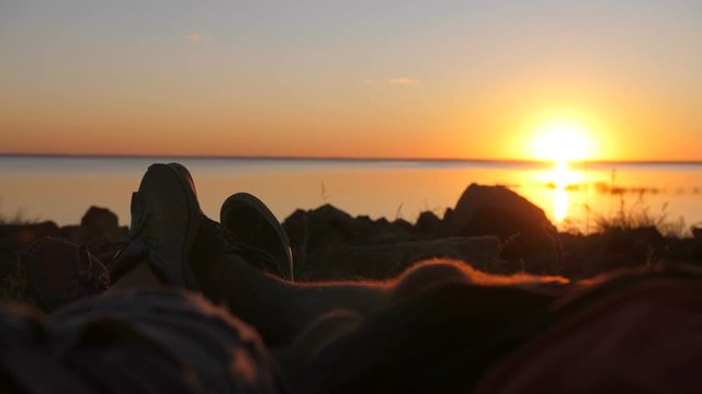 Close-up view of couple's feet cuddling in camping tent during sunset on the beach. Loving romantic moment of lovers enjoying nature and each other's company while watching the sea together