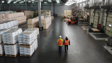 Rear view of warehouse team discussing while walking in warehouse. Aerial, top view. - Powered by Adobe