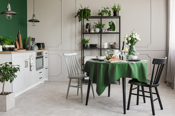 Fototapeta na wymiar Elegant grey and green kitchen with breakfast on round dining room table