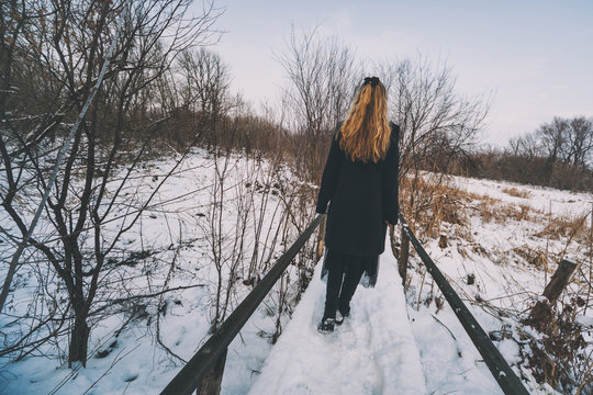 Lonely woman walking in park in winter.