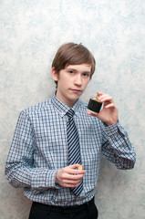 The young Russian guy holds a bottle of men's perfumery water in hand.