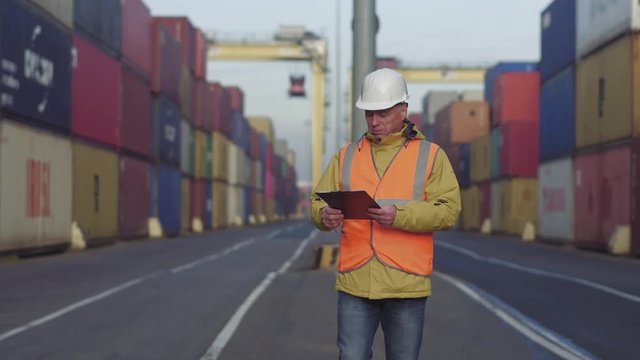 Caucasian 50s years old man making notes while checking terminal cargo dock.