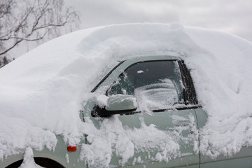A car with a lot of snow on top in Finland. The windshield is completely covered.