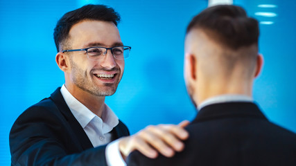 The happy businessmen pat on the shoulder in the office