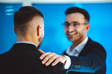 The two businessmen pat on the shoulder in the office