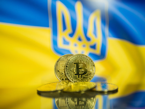 Bitcoin gold coin and defocused flag of Ukraine background. Virtual cryptocurrency concept.