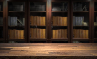 Blured bookshelf in small home library in the background. Table top for product display montage. Dark interior design.