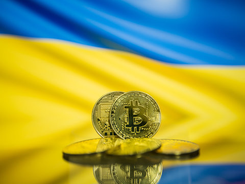 Bitcoin gold coin and defocused flag of Ukraine background. Virtual cryptocurrency concept.