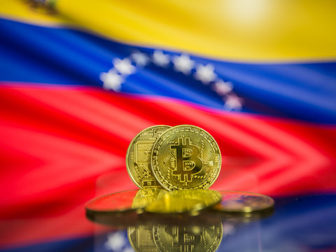Bitcoin gold coin and defocused flag of Venezuela background. Virtual cryptocurrency concept.