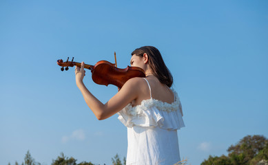 Beautiful asia girl white dress playing on a violin