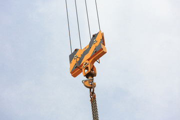 Crane load hook against the sky with trails and chain.