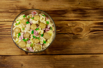 Obraz na płótnie Canvas Potato salad with marinated mushrooms, sausage, onion and mayonnaise on wooden table