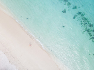 Aerial shot of woman looking up arms rised, enjoying the picture perfect white sand tropica beach on Mauritius island. Perfect tropical beach vacations concept.