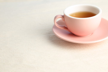 Hot black tea cup on beige fabric background