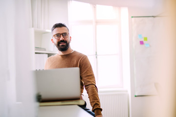 Fototapeta premium Mature hipster businessman with laptop working in a modern office.